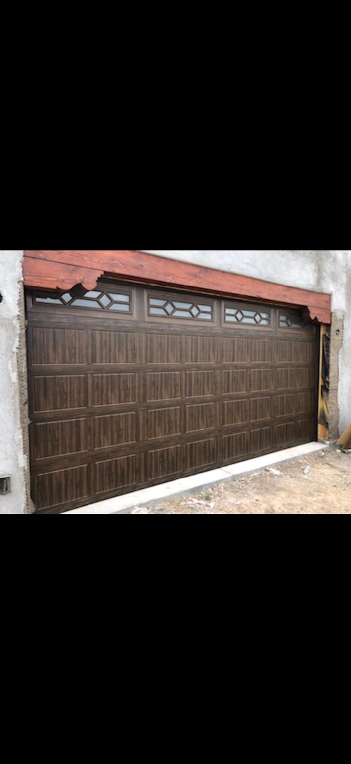 Garage door with wood-look panels and diamond pattern decorative windows